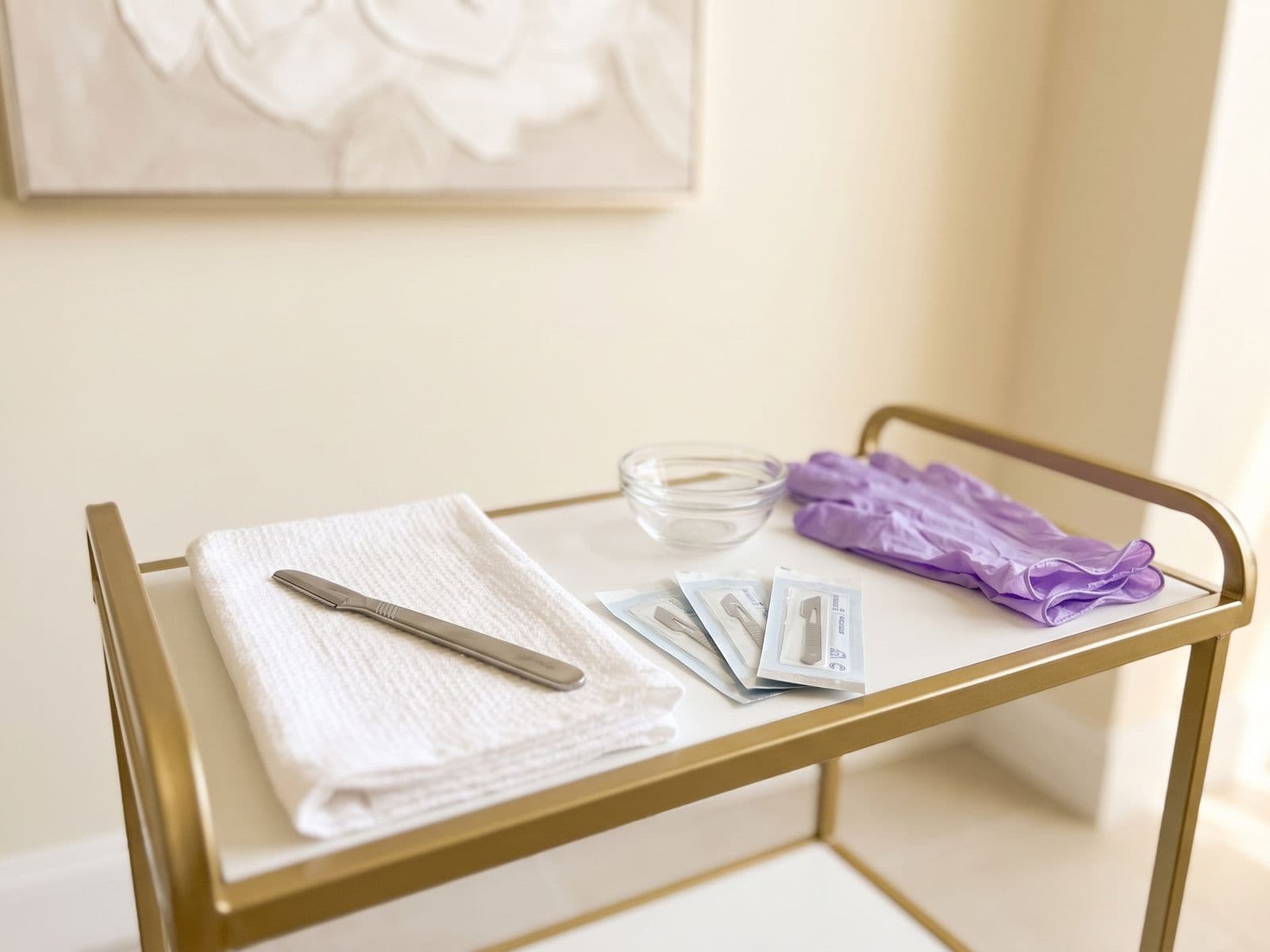 Close view of a dermaplaning handle and sealed sterile blades on a tray