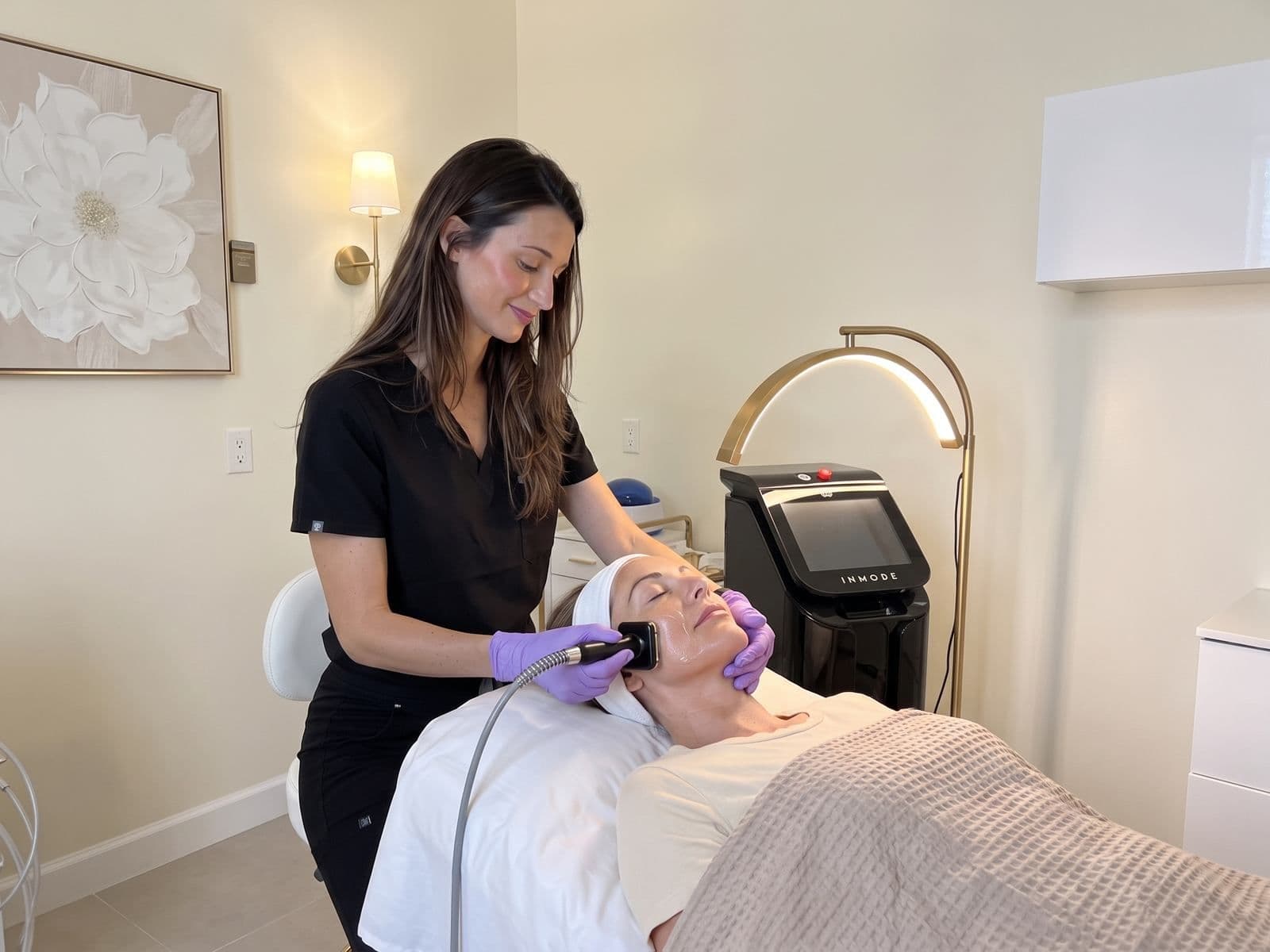A nurse gliding the InMode Forma handpiece along a cheek during the Hollywood Facial