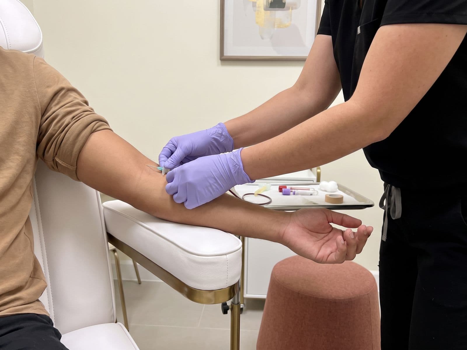 Gloved hands drawing a blood sample from a patient's arm for a menopause hormone lab panel